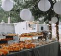 Stół w ogrodzie nakryty daniami z cateringu