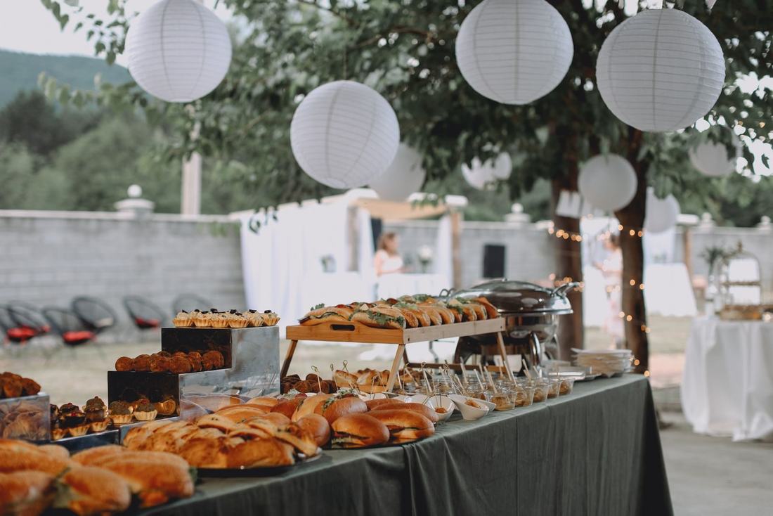 Stół w ogrodzie nakryty daniami z cateringu